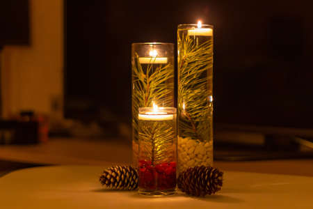 three candlesticks with floating candles of different heights, in candlesticks branches of pine and ateの写真素材
