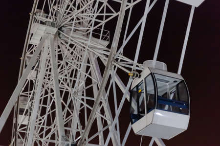 white Ferris wheel against the night sky, in the foreground a closed boothの写真素材