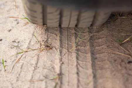 tyre tread print on yellow sand, on top of the car wheel with blurry background, used as a...