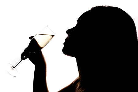 A girl drinks champagne from a glass on a white background, a black silhouetteの写真素材