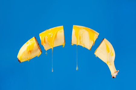 Not a peeled banana hangs in the air poured honey, drain drops of honey on a blue background, used as a background or text, conceptの写真素材