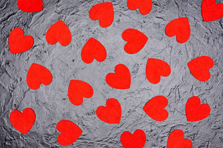 on a black factor background lies many red hearts, used as a background or texture, view from above