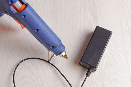 on the table lies a adhesive gun and an external power supplyの写真素材