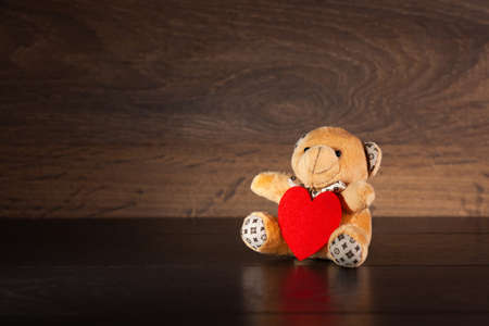 Little teddy bear with red heart on a wooden background, used as a backgroundの写真素材