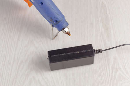 on the table lies a adhesive gun and an external power supplyの写真素材
