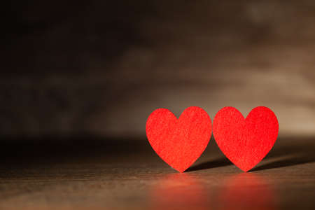 Against the background of a dark tree two red hearts, use as a background or postcardの写真素材