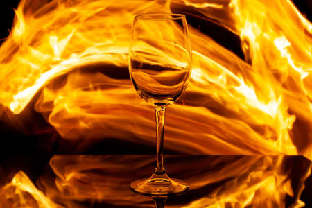 empty wine glass on fire on a dark background, used as a background or textの写真素材