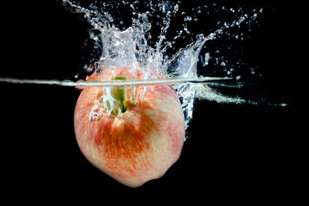 ripe red apple fell into the water with splashes