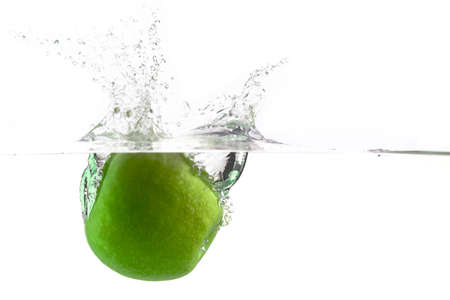 drop one green apple into the water with splashes on a white backgroundの写真素材