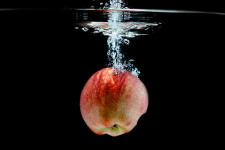 one red ripe apple falls into the waterの写真素材