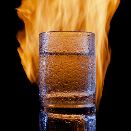 sweating glass of water on fire on a black backgroundの写真素材