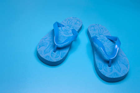 Blue rubber flip-flops isolated over blue background, pair of thongs, shot aboveの写真素材
