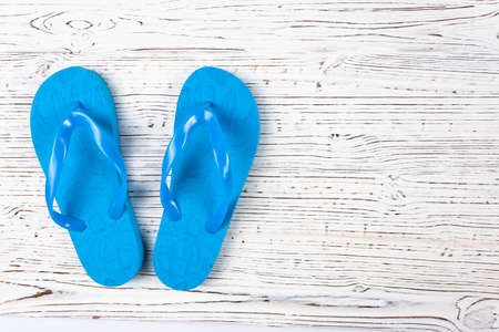 blue rubber slippers on a white wooden background, view from above, place under the text