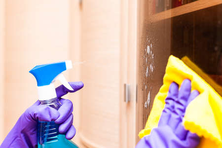 female hands in gloves wipe the glass of the cabinetの写真素材