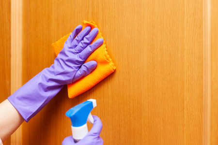 hand in a purple rubber glove rubs the brown door, close-upの写真素材