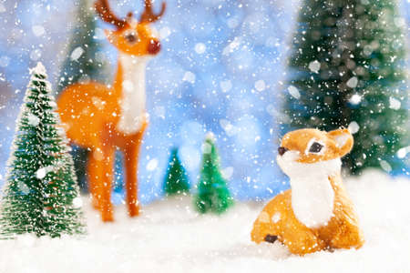 two little deer on the New Years greeting card. Blurred blue background. Toy pine treesの写真素材