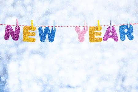 Shiny letters on clothespins, the inscription New Year. Blurred shiny white-blue background. Place for the text. Template for greeting cardの写真素材