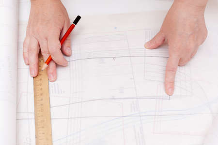 Female hands do the layout of the sewing pattern on paper