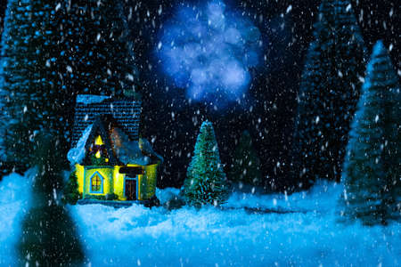 fabulous winter house in the forest at night, the moon is shining, it is snowing. New year greeting cardの写真素材