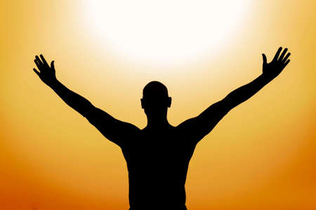 Silhouette of a man with open arms facing the sunの写真素材