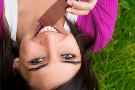 Young woman eating chocolate outdoorsの写真素材