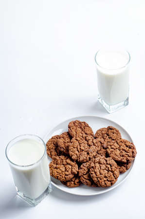chocolate chip cookies and glass of milk on white backgroundの写真素材