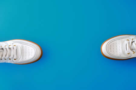 White sneakers with pastel blue background. Men's shoes. Composition with copy space. Minimal...