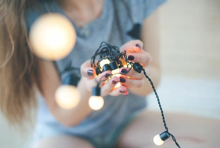 Close up of young woman holding garlands of lightsの写真素材
