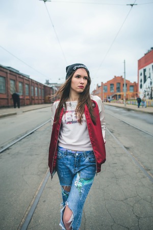 Urban lifestyle portrait of young cute girl in a hat walking on the streetの写真素材