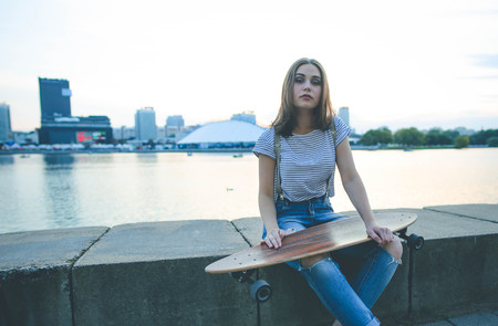 Portrait of young stylish hipster girl with longboard skateboard in a urban backgroundの写真素材