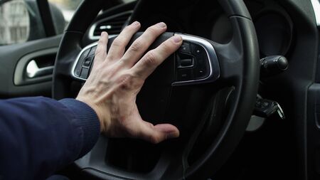 Hand of the car driver on the steering wheel horn, beepingの写真素材