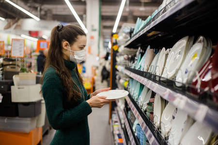 Young woman choosing dinner utensil plate in supermarket.の写真素材