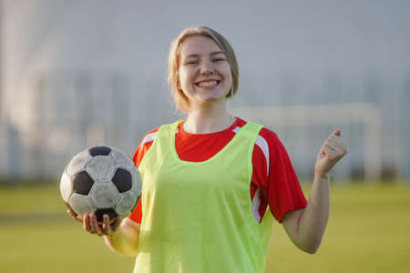Happy female football player in sportwear celebrating victory, holding soccer ballの写真素材