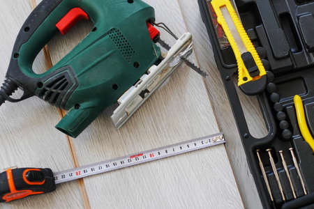 Set of assorted work tools, electric jigsaw and tape measure lies on the laminate.の写真素材