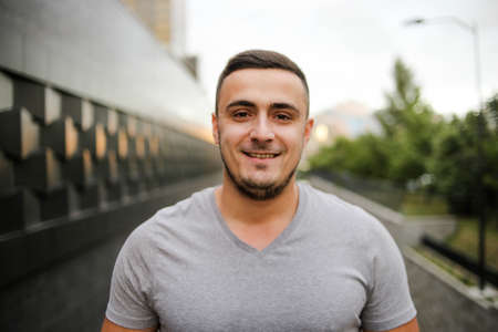 Young smiling jewish man wearing gray t shirt walking on the street. Handsome young man looking at camera.の写真素材