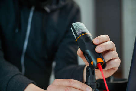 Closeup hand of young man podcast creator or radio host taking microphoneの写真素材