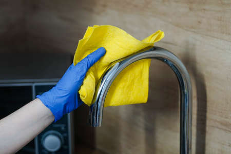 Young Woman In Gloves Cleaning The Steel Tap In The Kitchen.の写真素材