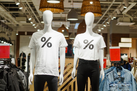 Two dummies mannequins wearing white shirts with percent sign in clothing store. Sales discounts concept. Black Friday.の写真素材