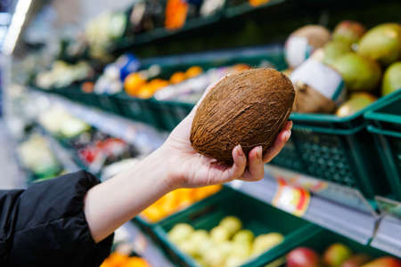Woman customer choosing ripe coconut at supermarket. Close up.の写真素材