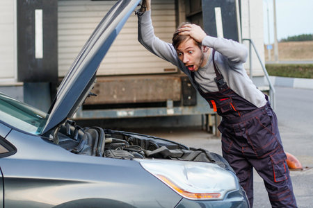 Shocked technician mechanic looks inside the car. Engine trouble.