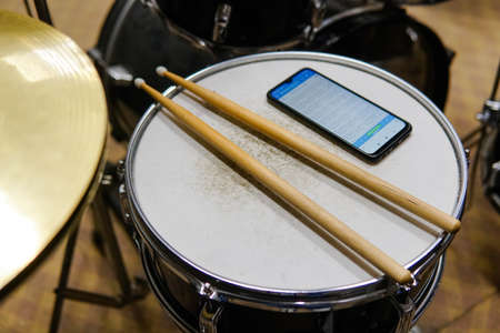 Close up of drum sticks and smartphone. Music online learning.の写真素材