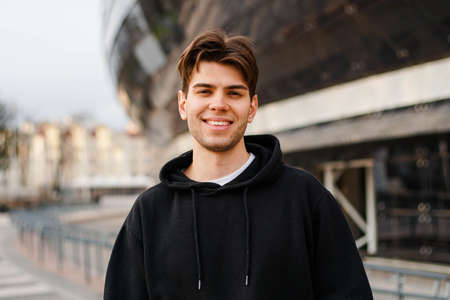 City portrait of smiling hipster guy wearing black hoodie.の写真素材