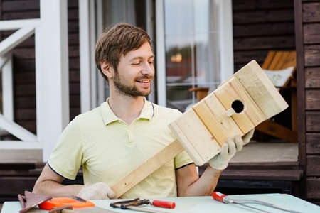 Portrait of smiling craftsman carpenter making a wooden birdhouse. DIY concept.の写真素材