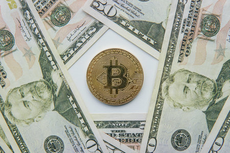 Close up of golden bitcoin crypto currency coin on US dollar bills. Crypto investing cryptocurrency...