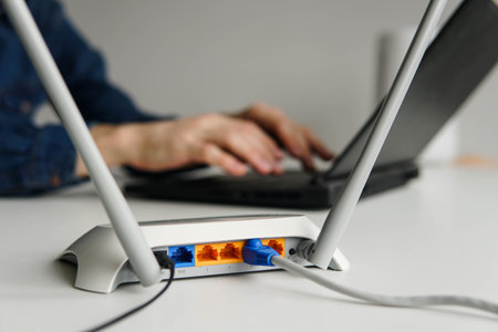 Wireless high speed wifi router on the table. Man using laptop on the backgroundの写真素材