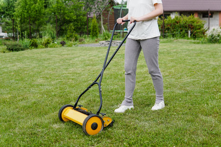 Young woman mowing lawn with a manual push lawn mowerの写真素材
