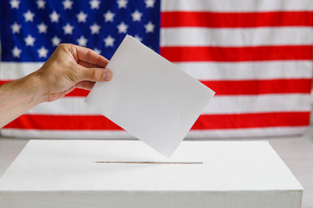 Man putting a ballot into a voting box. USA American flag on the background.