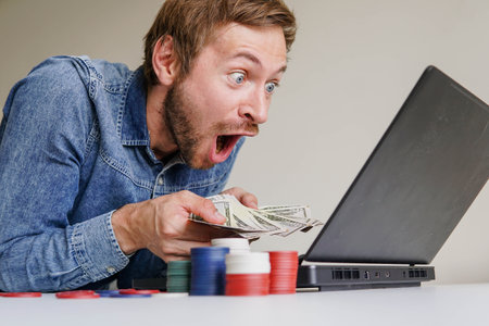 Online poker or casino roulette player sitting in front of laptop exited for winning the tournamentの写真素材