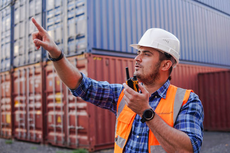 Container man worker in white helmet talking radio phone or walkie-talkie in container warehouse.の写真素材