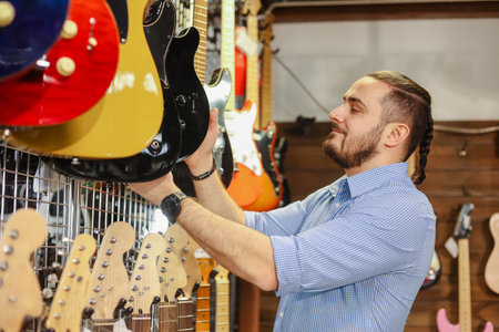 Handsome bearded man choosing electric guitar in a musical instrument store.の写真素材